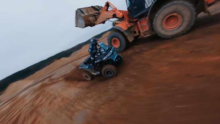 Keturratis pravažiuoja pro sunkiają techniką karjero teritorijoje